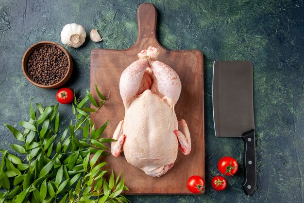 Pollo fresco vista dall'alto con foglie verdi su superficie blu scuro