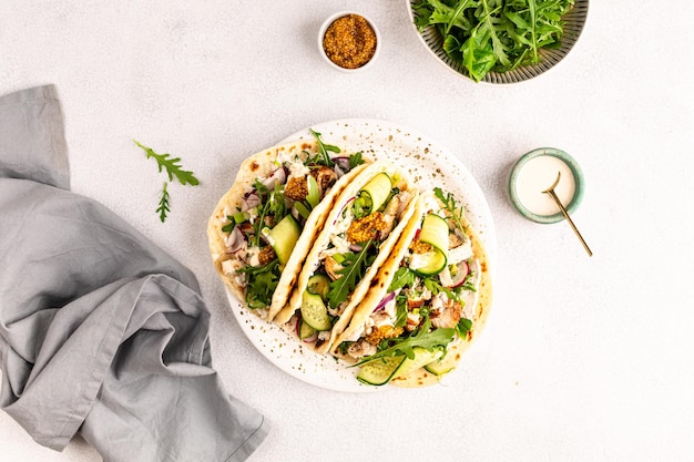 Pollo fritto, arugula, cetriolo, radice, cipolla rossa e salsa di tortilla di grano per pranzo, deliziosi burritos o tacos messicani.