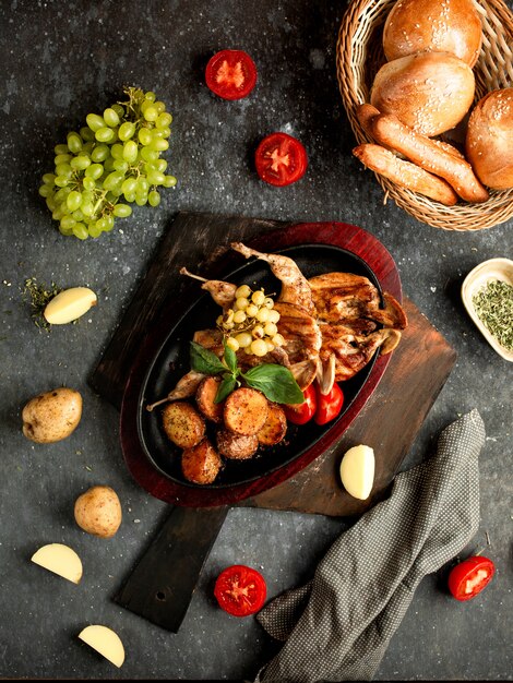 Pollo fritto con patate, pomodori e uva