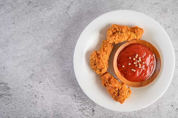 Pollo fritto croccante su un piatto bianco con salsa al pomodoro