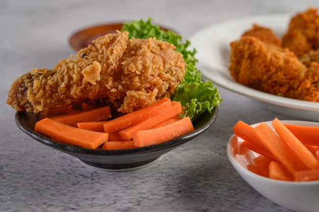 Pollo fritto croccante su un piatto con insalata e carota