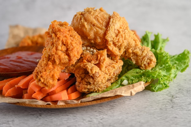 Pollo fritto croccante su un piatto con salsa al pomodoro e carota