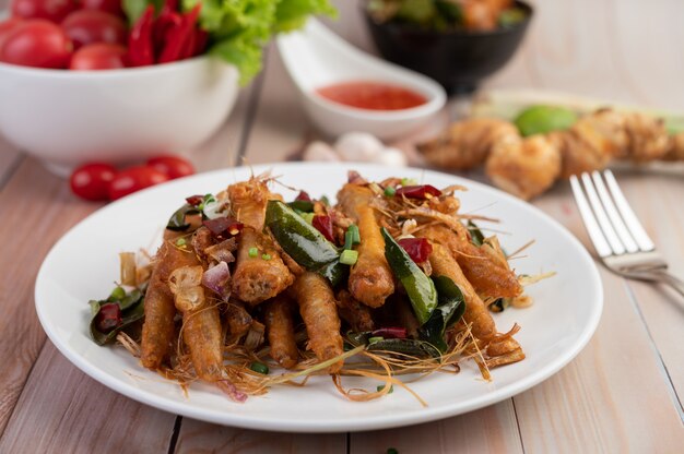 Pollo fritto dell'erba su un piatto bianco su un pavimento di legno.