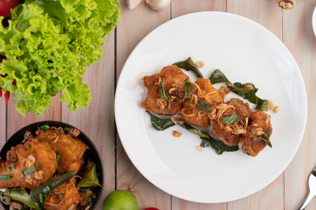 Pollo fritto dell'erba su un piatto bianco su un pavimento di legno.