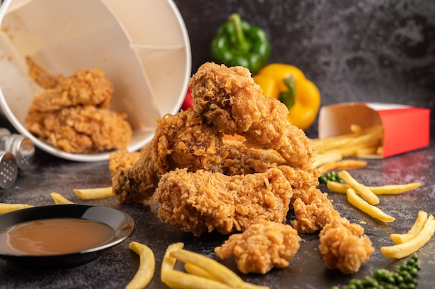 Pollo fritto e patatine fritte sul pavimento di cemento nero.