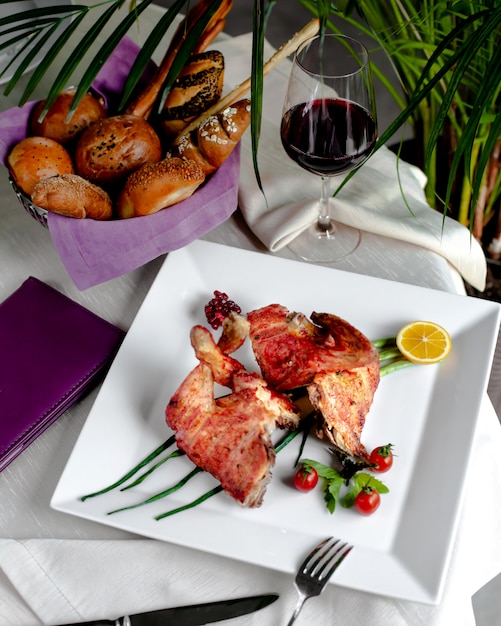 Pollo fritto servito con pomodorini, pane e bicchiere di vino