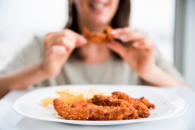 Pollo fritto vicino a mangiare donna