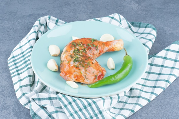 Pollo marinato con aglio e pepe sulla zolla blu.