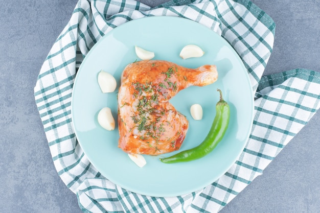 Pollo marinato con aglio e pepe sulla zolla blu.