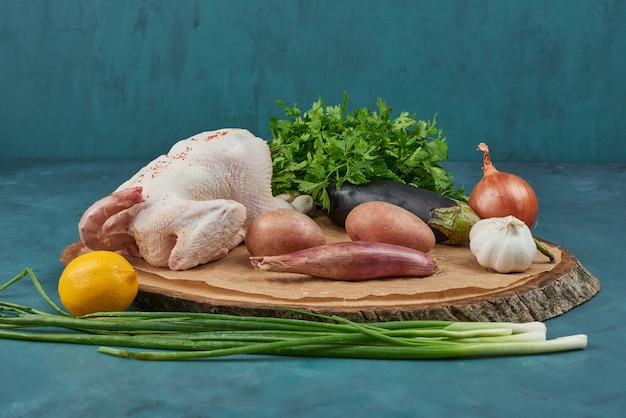 Pollo su una tavola di legno con verdure.