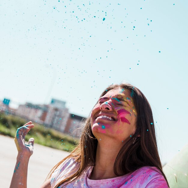 Polvere blu di holi sopra la giovane donna sorridente all&#39;aperto