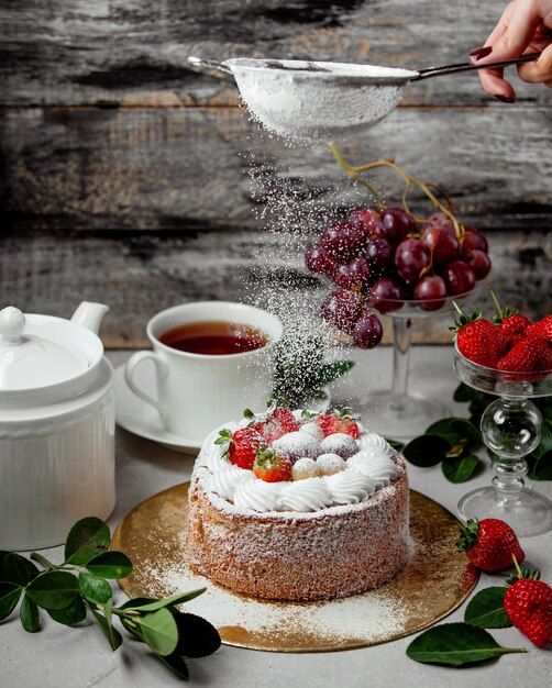 Polvere dello zucchero del setaccio della donna sulla torta della frutta