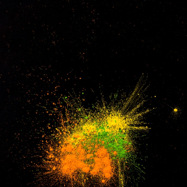 Polvere di colore giallo, verde e arancione schiacciata su sfondo nero