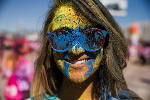 Polvere di colore holi blu e giallo sul viso di donna