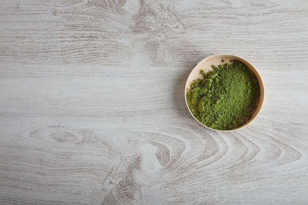 Polvere di tè matcha premium biologico vista dall'alto in una scatola di legno isolato sul tavolo semplice bianco da solo