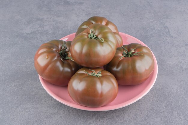 Pomodori appetitosi nel piatto, sulla superficie di marmo