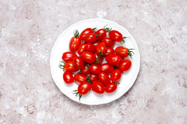 Pomodori ciliegia di vari colori, pomodori ciliegia gialli e rossi su sfondo chiaro