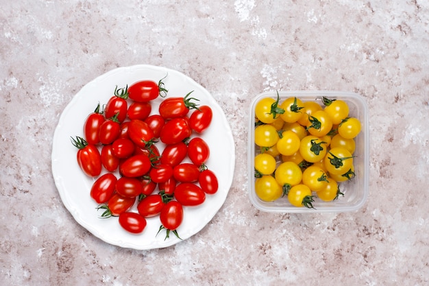Pomodori ciliegia di vari colori, pomodori ciliegia gialli e rossi su sfondo chiaro