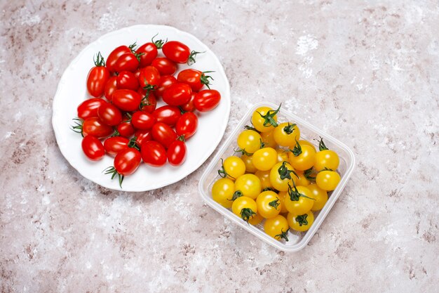 Pomodori ciliegia di vari colori, pomodori ciliegia gialli e rossi su sfondo chiaro