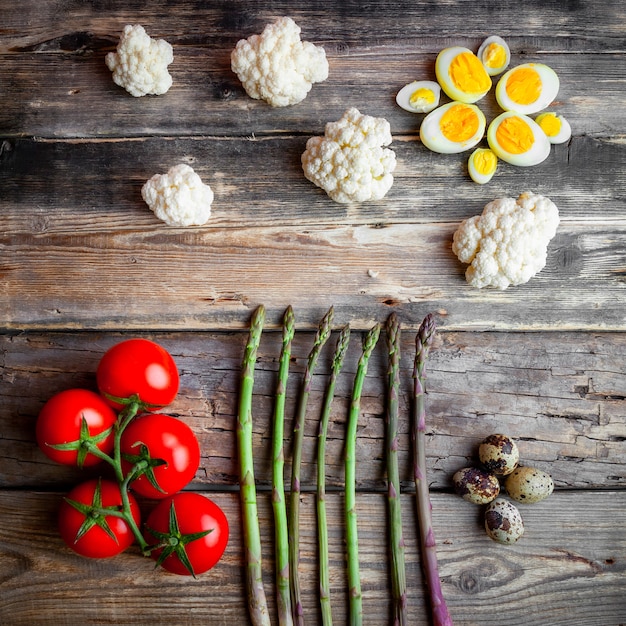 Pomodori con asparagi, uova, vista dall'alto di cavolfiore su un fondo di legno scuro