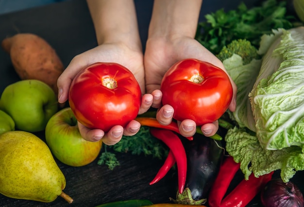 Pomodori del primo piano in mani femminili in cucina