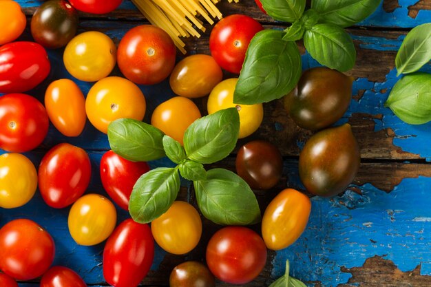 Pomodori diversi colori colorati con basilico su legno vecchio sfondo rustico. Vista dall&#39;alto. Orizzontale. Concetto di cibo.