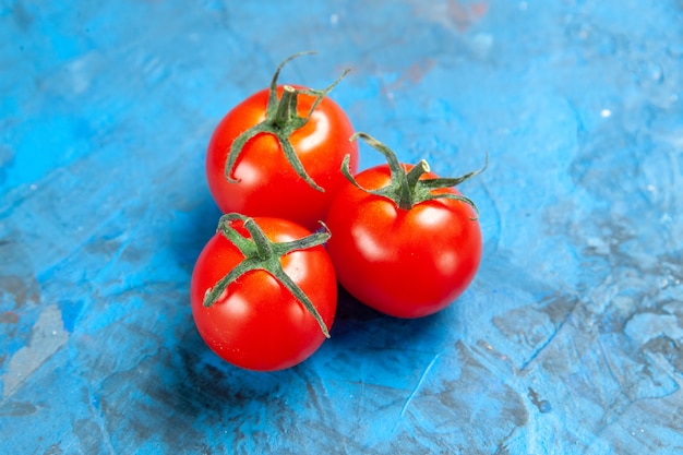 Pomodori freschi di vista frontale sul tavolo blu