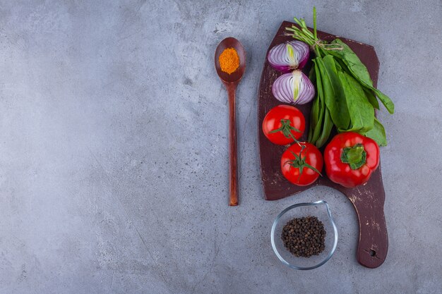 Pomodori freschi e cipolla con vari condimenti su tavola di legno.