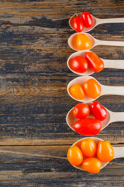 Pomodori freschi in cucchiai di legno su una tavola di legno. disteso.