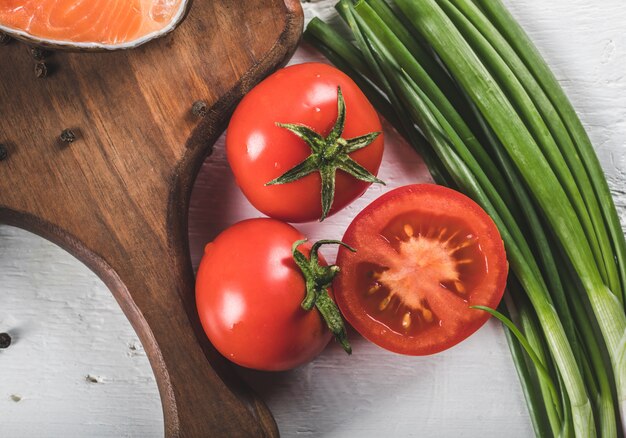 Pomodori freschi interi e tagliati a metà con erbe verdi