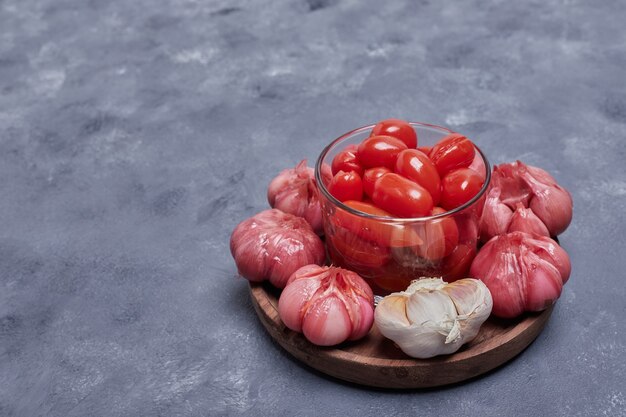Pomodori marinati e aglio sul piatto di legno.