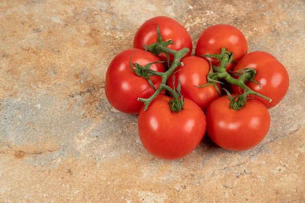 Pomodori rossi ciliegia su un ramo sulla superficie di marmo.