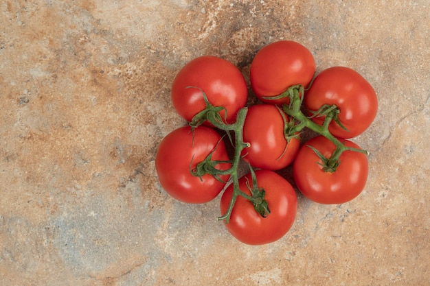 Pomodori rossi ciliegia su un ramo sulla superficie di marmo