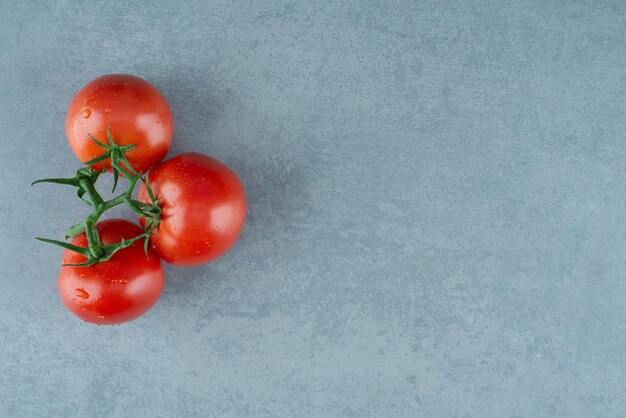 Pomodori rossi con gocce d'acqua sul blu.