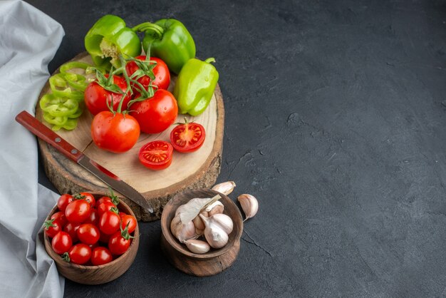 Pomodori rossi freschi di vista frontale con aglio e peperoni verdi su superficie scura