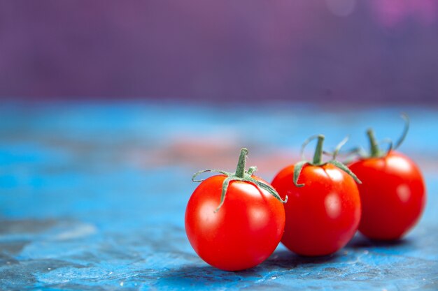 Pomodori rossi freschi di vista frontale sul tavolo blu