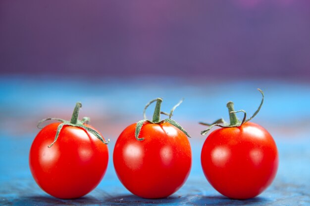 Pomodori rossi freschi di vista frontale sul tavolo blu