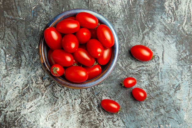 Pomodori rossi freschi di vista superiore all'interno del piatto sull'insalata scura della foto della frutta della tavola scura