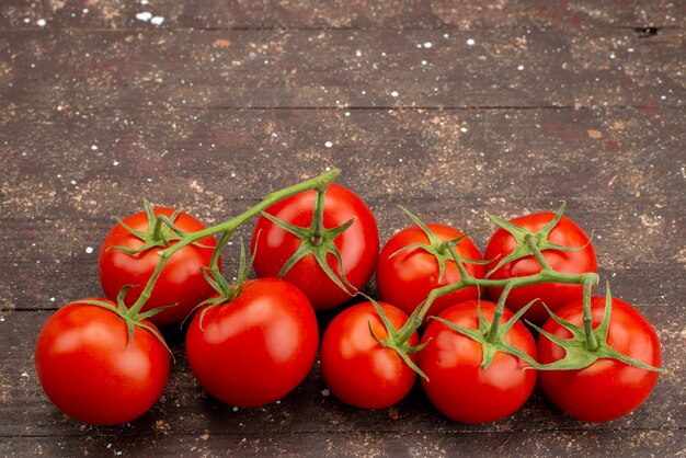 Pomodori rossi freschi di vista superiore maturi e interi su marrone di legno