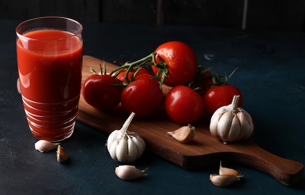 Pomodori rossi, guanti all'aglio e un bicchiere di succo di pomodoro.