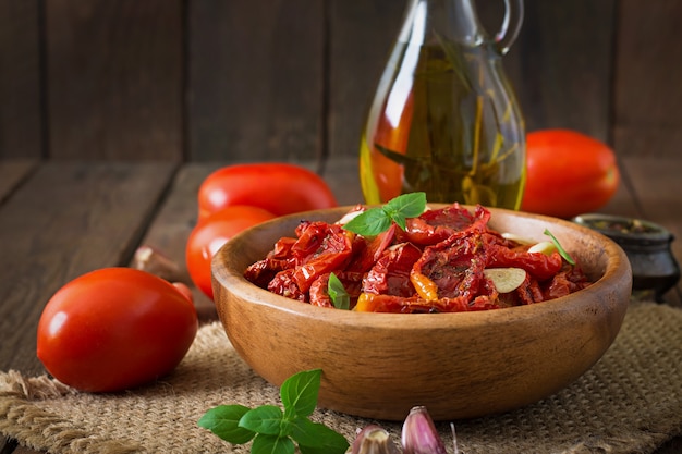 Pomodori seccati al sole con erbe e aglio in ciotola di legno