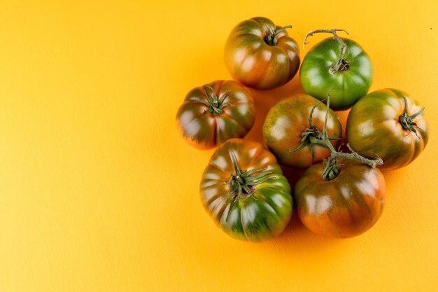 Pomodori verdi a sinistra del telaio con copia spazio sulla superficie gialla