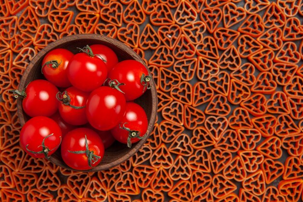 Pomodori vista dall'alto in ciotola su pasta cuore rosso