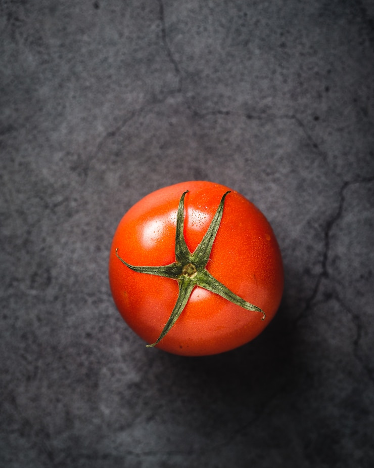 Foto gratuito pomodoro su cemento grigio