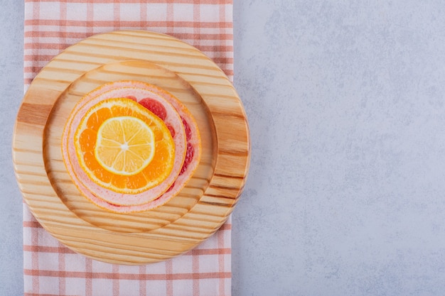 Pompelmo fresco, limone e anelli di arancia sul piatto di legno.