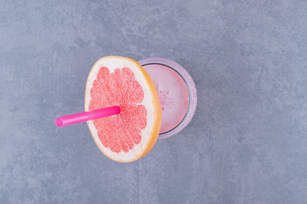 Pompelmo maturo con un bicchiere di succo sul primo piano del tavolo.