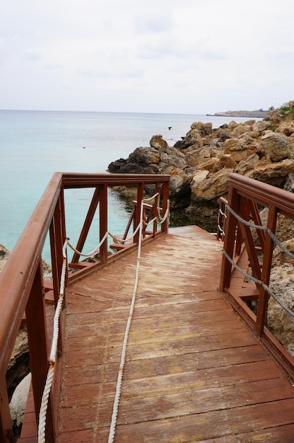 pontile in legno vicino al mare con una costa rocciosa