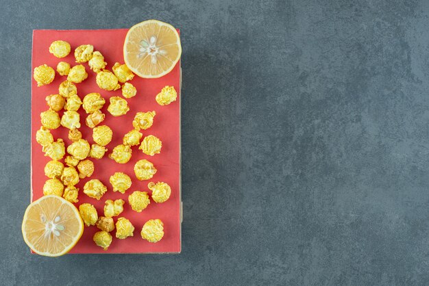 Popcorn al caramello su una tavola di legno accanto a fette di limone su fondo marmo. Foto di alta qualità