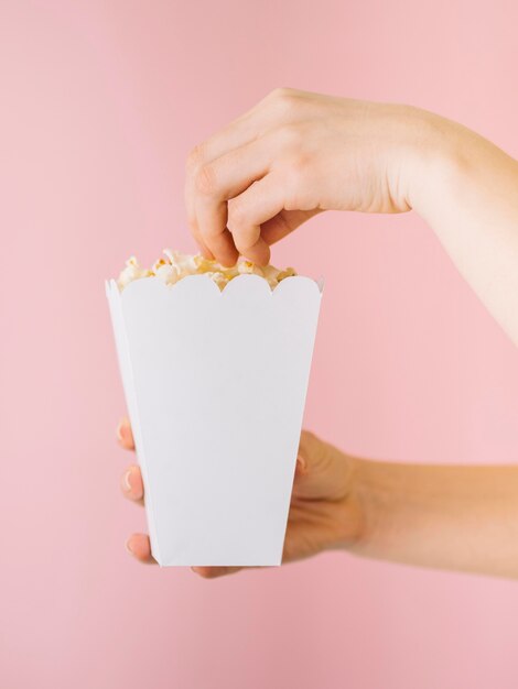 Popcorn di raccolto della mano del primo piano dalla scatola