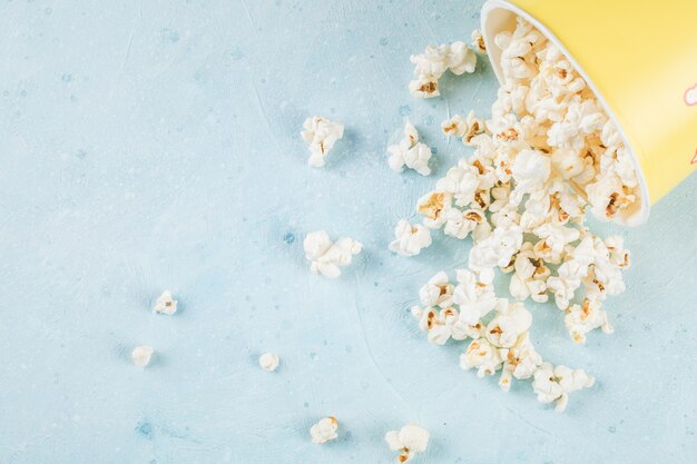 Popcorn freschi sparsi sul tavolo blu fuori dalla scatola
